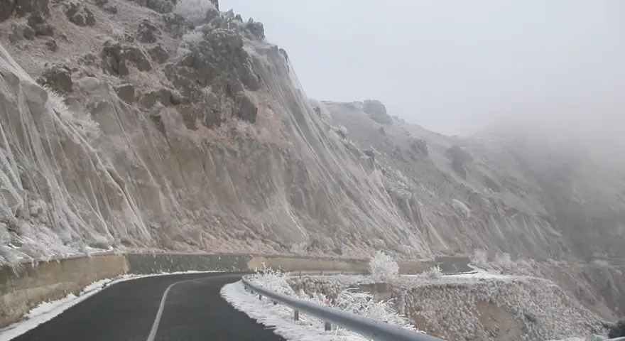 Strada innevata al passo del Faiallo, con rocce e vegetazione ghiacciate.