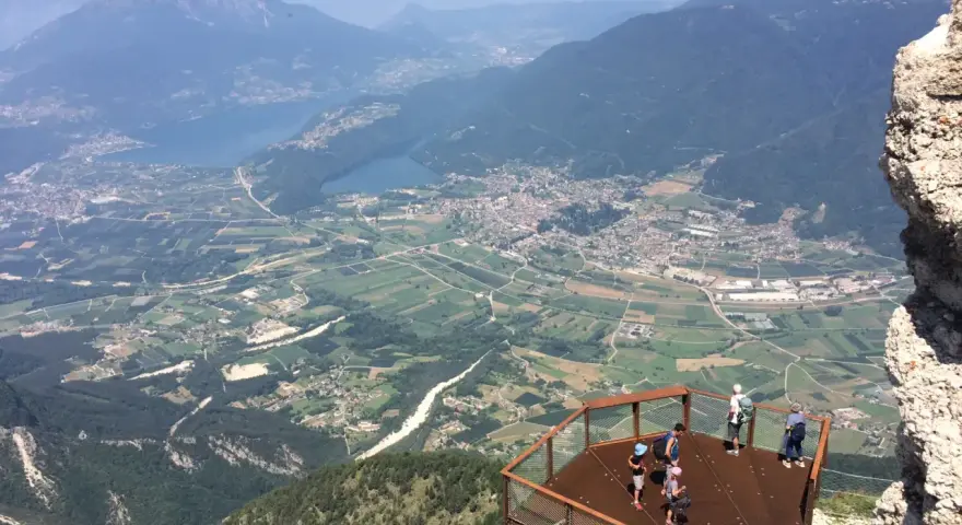 Vista panoramica dal Pizzo di Levico con un punto panoramico e persone che ammirano la valle sottostante.