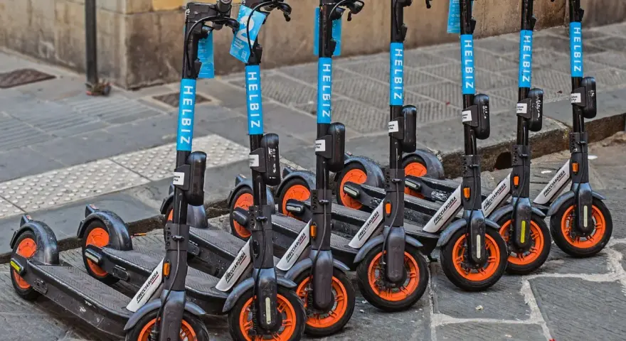 Monopattini elettrici Helbiz in fila, pronti per l'uso. La loro assicurazione è fondamentale per una mobilità sicura.