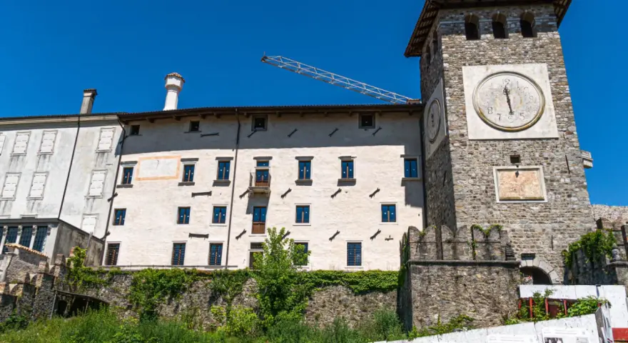 Torre dell'orologio e palazzi storici a Colloredo di Monte Albano, sotto un cielo azzurro.