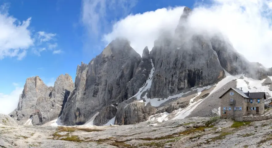 Rifugio Mulaz da Passo Valles, un'oasi di pietra tra le vette dolomitiche avvolte dalle nuvole.