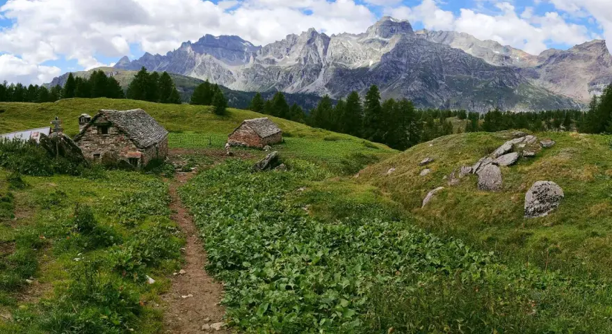 Sentiero per alpe devero trekking tra baite in pietra e montagne maestose.