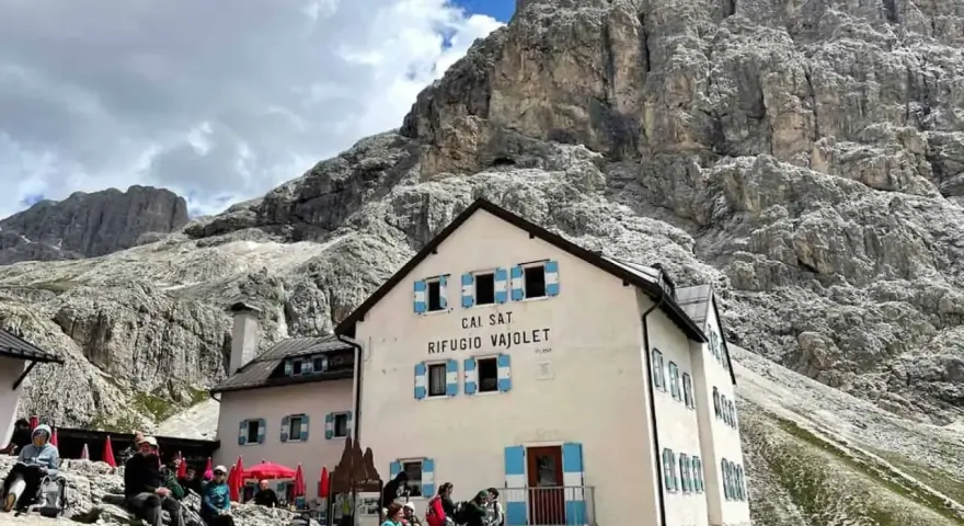 Rifugio Vajolet, punto di partenza per un percorso facile verso le Torri del Vajolet. Persone riposano sotto le imponenti rocce.