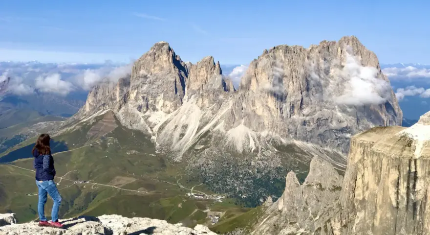 Ragazza ammira la terrazza delle Dolomiti. Per arrivare, prendi la funivia da Canazei.