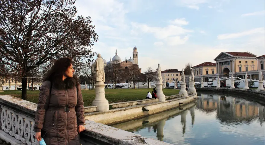 Una donna ammira il panorama di Padova in un giorno d'inverno, con statue, canali e la Basilica di Sant'Antonio sullo sfondo.