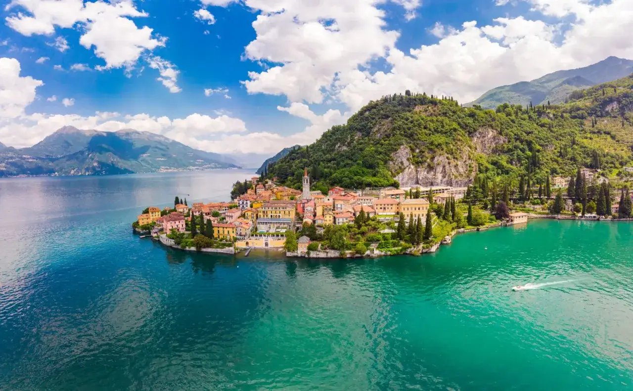 Varenna centro storico, un gioiello sul lago di Como, con case colorate che si affacciano sull'acqua turchese e montagne verdi sullo sfondo.
