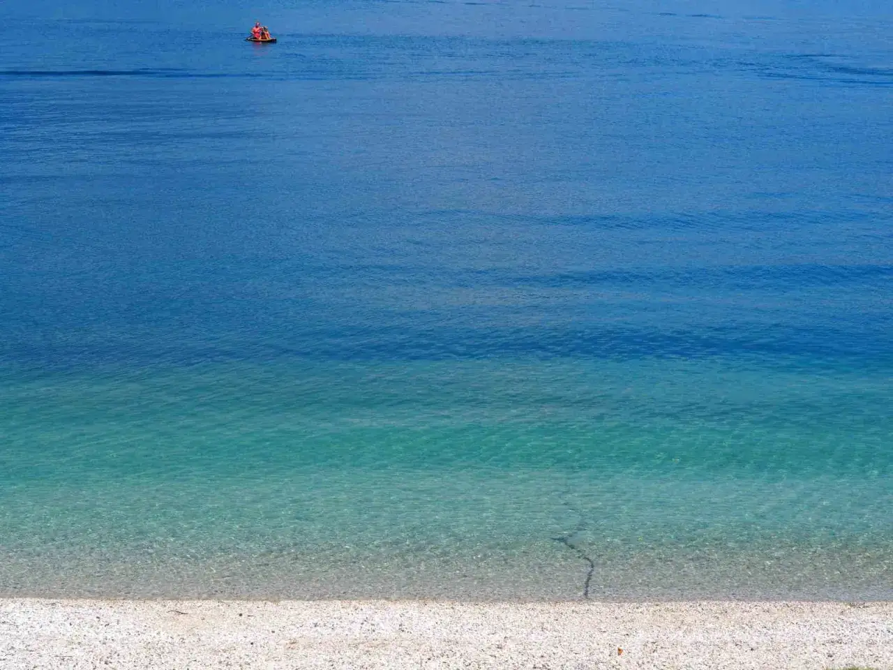 Acque cristalline e una persona su una tavola da SUP nella baia delle sirene a Garda.