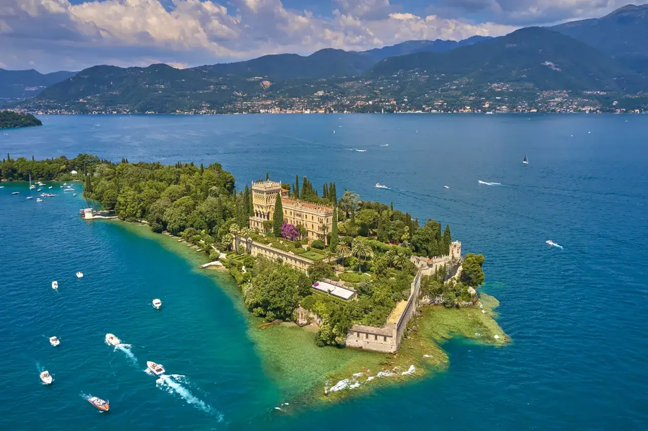 Villa Borghese, una delle isole del Lago di Garda, con il suo imponente palazzo e giardini lussureggianti, circondata da acque cristalline e piccole imbarcazioni.