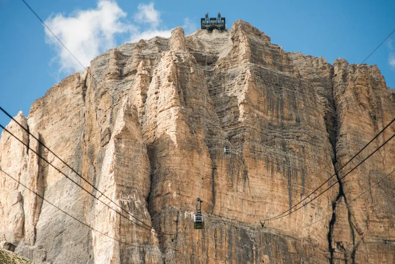 Funivia per la terrazza delle Dolomiti. Due cabine salgono verso la cima rocciosa, offrendo un modo spettacolare per raggiungere la vetta.