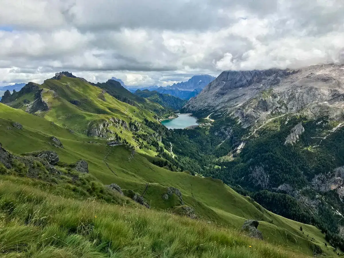 Panoramica mozzafiato delle Dolomiti con il lago Fedaia. Per raggiungere il rifugio Viel del Pan, segui i sentieri verdi che si snodano tra le montagne.