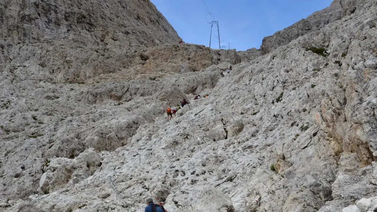 Escursionisti affrontano la difficolt&agrave; del sentiero roccioso verso il Rifugio Re Alberto. Cavi d'acciaio aiutano la salita.