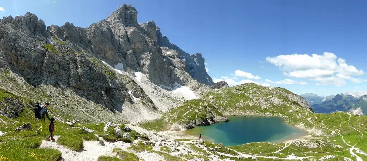 Escursionisti sul sentiero che porta al lago alpino sotto il maestoso Monte Civetta.