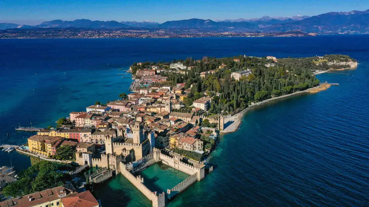 Il centro storico di Sirmione, con il suo castello sul lago e le case colorate, si estende su una penisola circondata da acque azzurre.