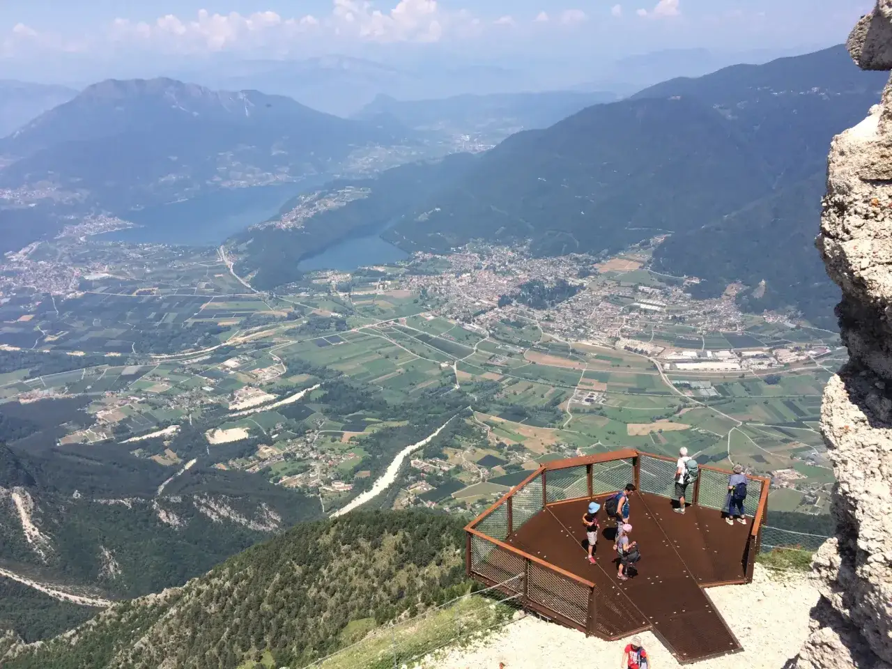 Vista panoramica dal Pizzo di Levico con un punto panoramico e persone che ammirano la valle sottostante.