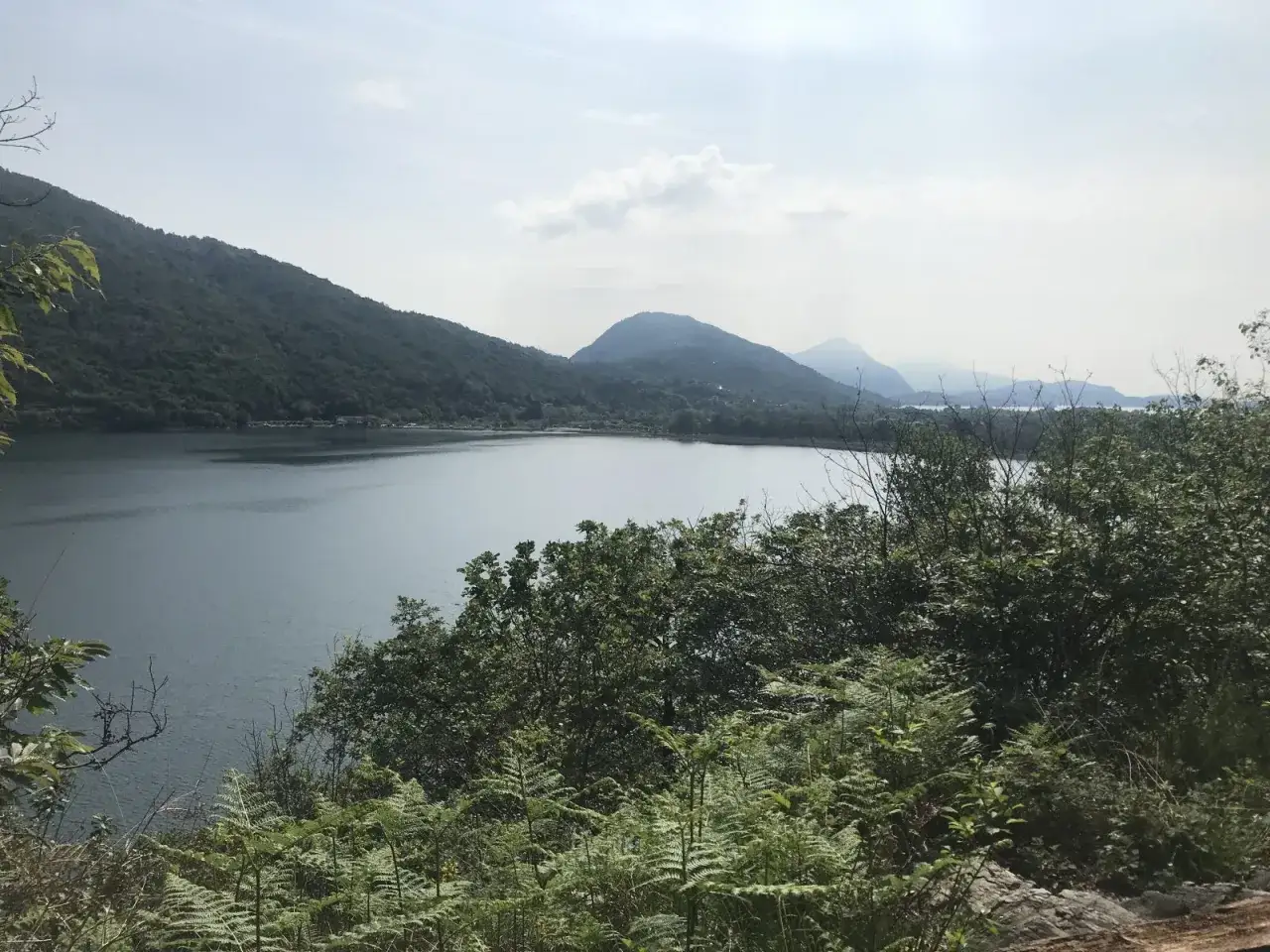 Vista panoramica del sentiero azzurro Mergozzo, con il lago calmo e le montagne verdi sullo sfondo.