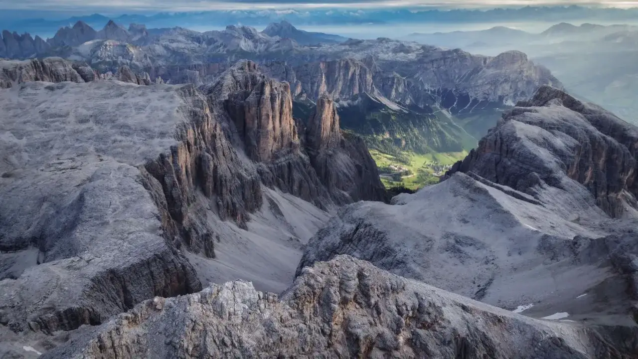 Viste mozzafiato dalle cime rocciose del Piz Bo&egrave;, con un villaggio verdeggiante in lontananza.