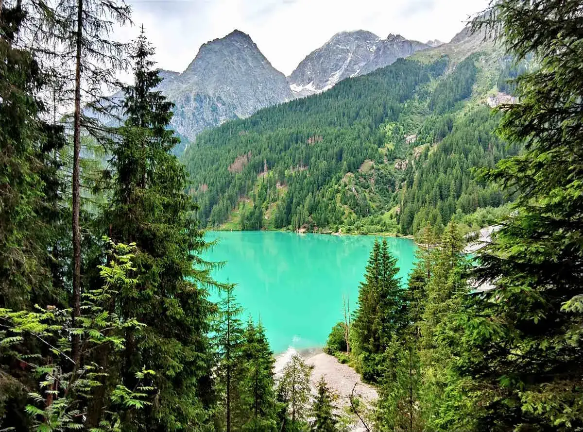 Vista incantevole dell'Antholzer See, un lago alpino dalle acque turchesi, incorniciato da fitti boschi di conifere e maestose montagne.