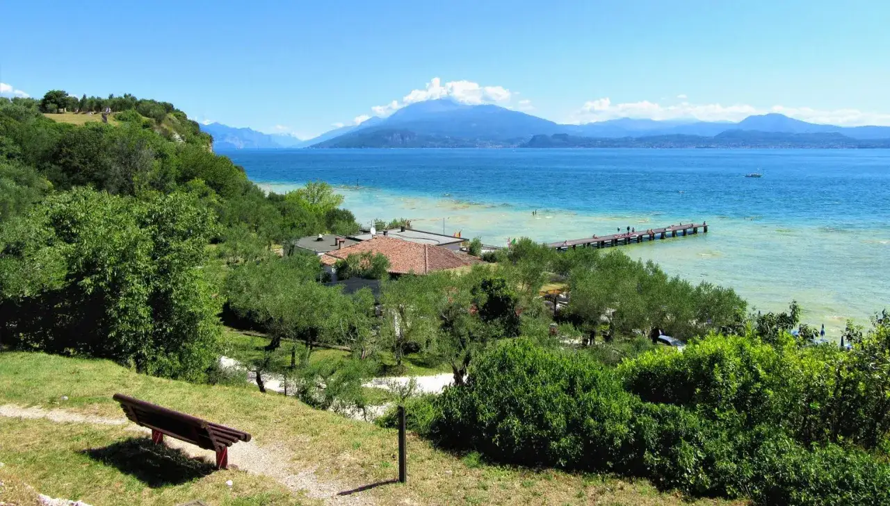 Panoramica del lido delle bionde con lago, montagne, molo e vegetazione lussureggiante.