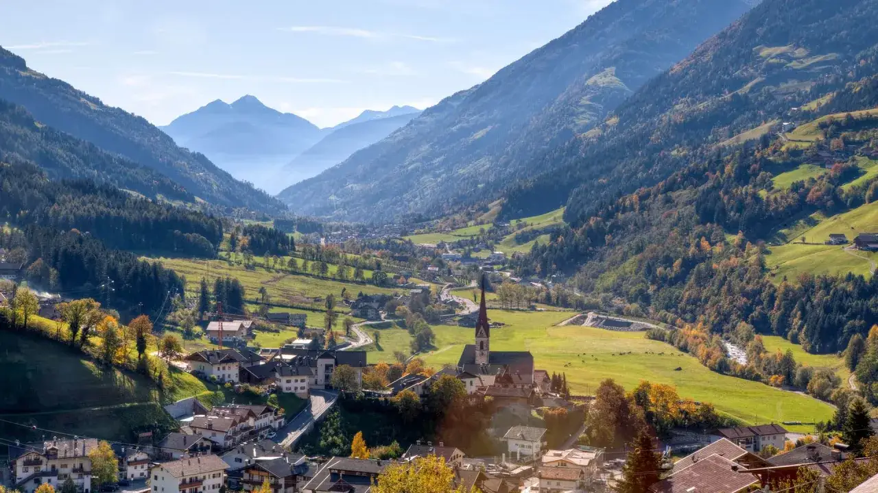 San Leonardo in Passiria, un pittoresco villaggio alpino incastonato tra montagne verdi e boschi autunnali.