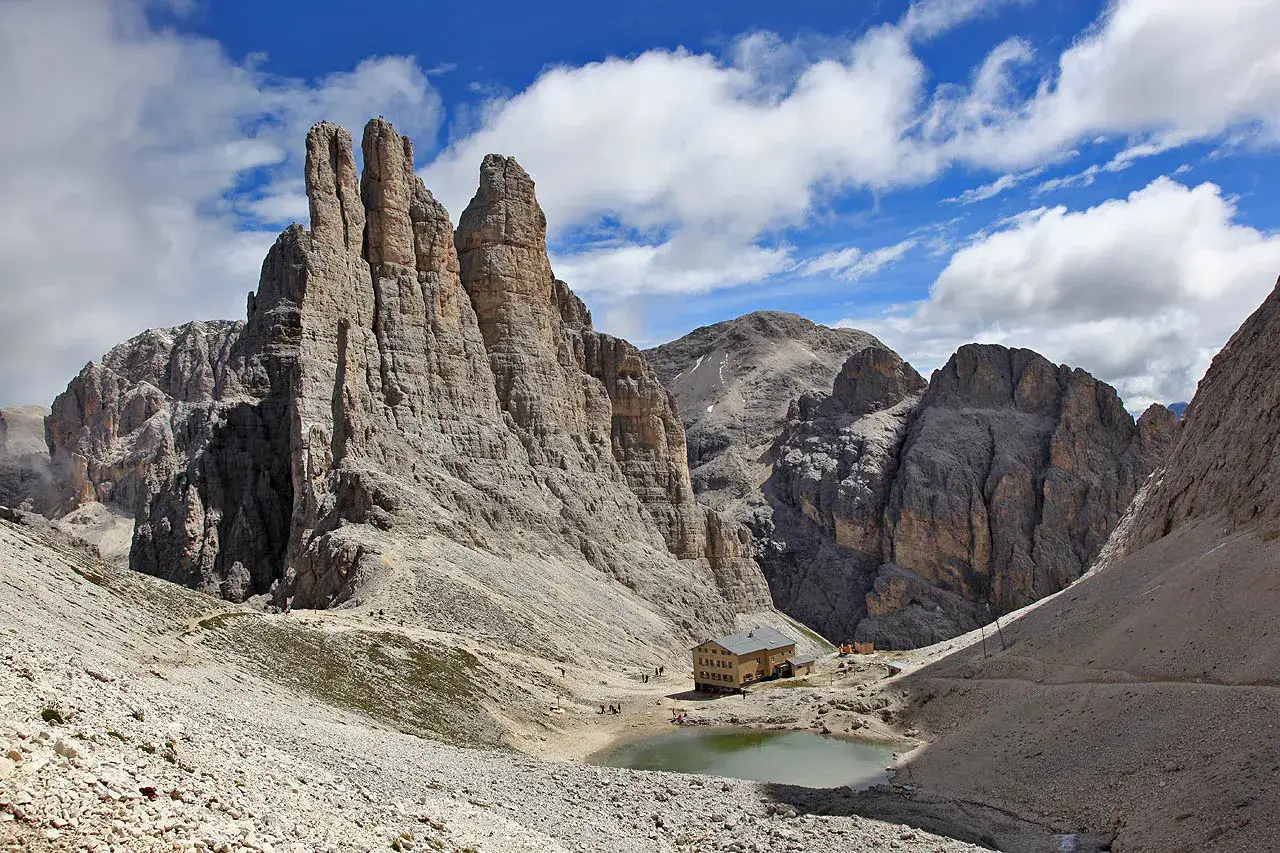 Torri del Vajolet: un rifugio alpino e un laghetto ai piedi delle imponenti torri, con un percorso facile che attraversa un paesaggio roccioso.