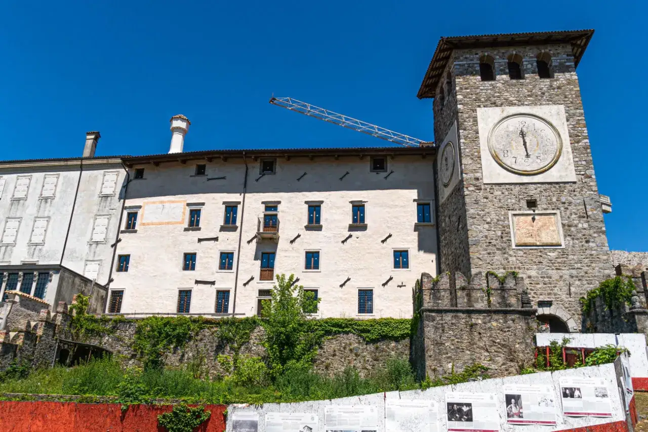 Torre dell'orologio e palazzi storici a Colloredo di Monte Albano, con un cantiere in corso.