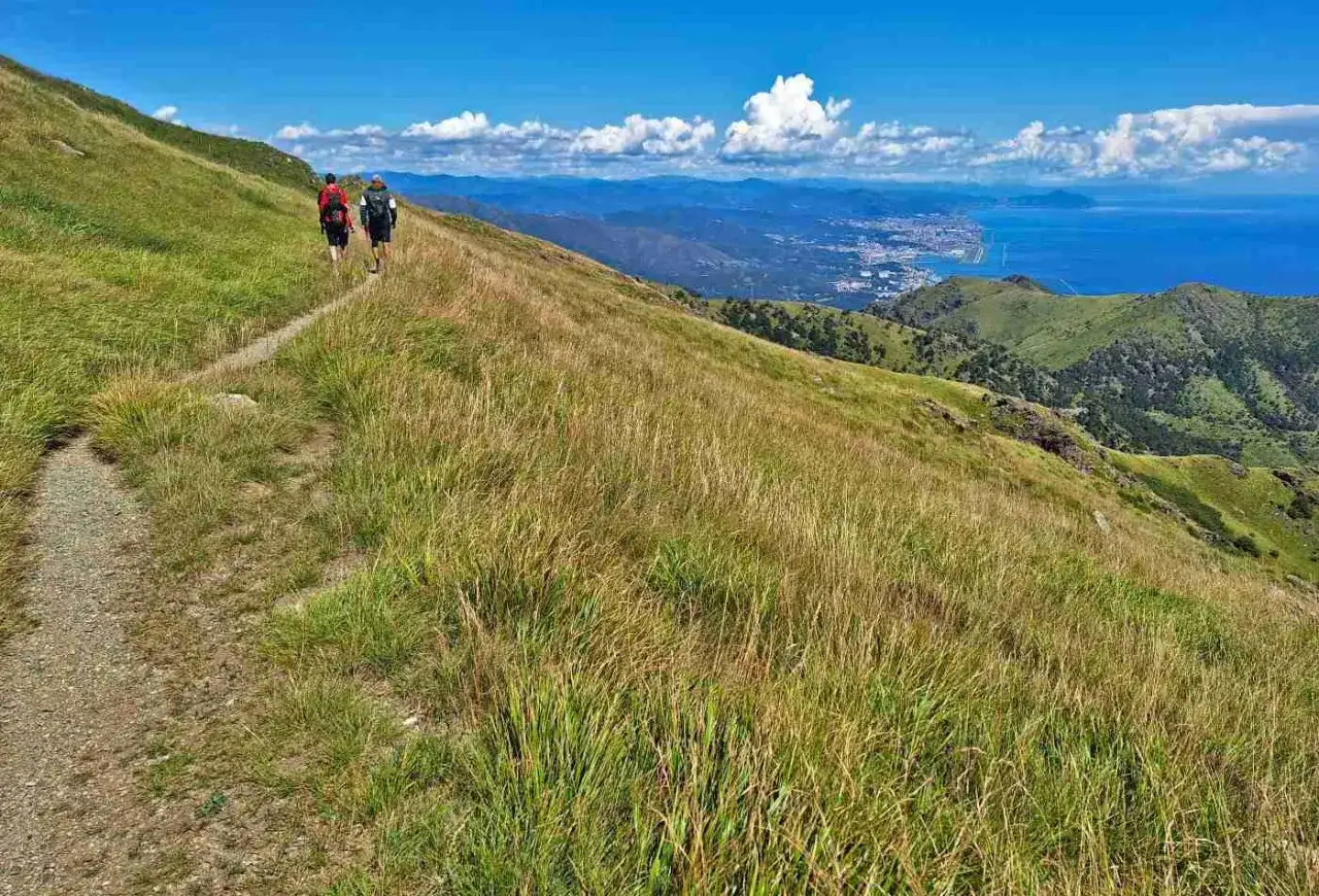 Escursionisti sul sentiero del Passo del Faiallo, con vista sul mare e sulla costa in lontananza.