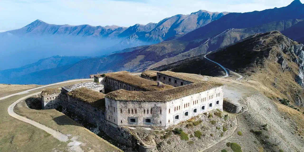 Fortificazioni storiche a Cismon del Grappa, con tetti erbosi e montagne sullo sfondo.