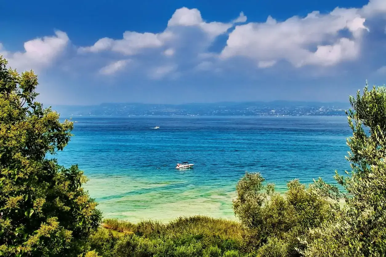 Vista incantevole del Lago di Garda, con acque turchesi e una barca che naviga vicino alla manerba del garda strand.