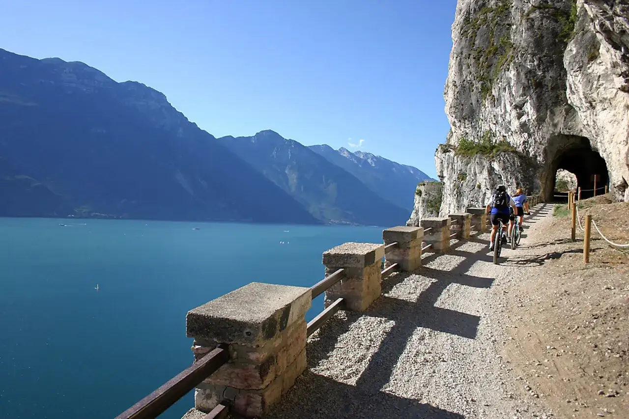 Ciclisti sul sentiero del Ponale, un giro ad anello panoramico con vista sul lago e montagne.