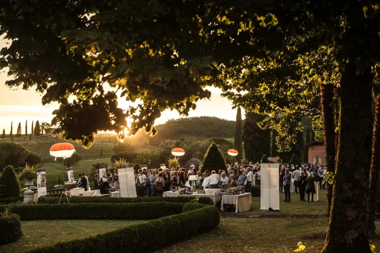 Serata elegante in un giardino tra Modena e Reggio Emilia, con palloni luminosi e gente che socializza.