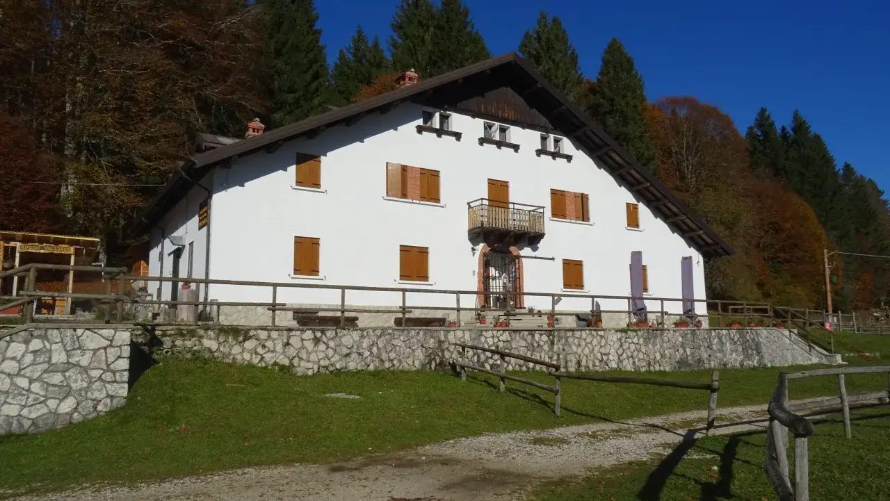Il rifugio Citt&agrave; di Vittorio Veneto, immerso nel foliage autunnale, accoglie i visitatori con la sua facciata bianca e le persiane in legno.