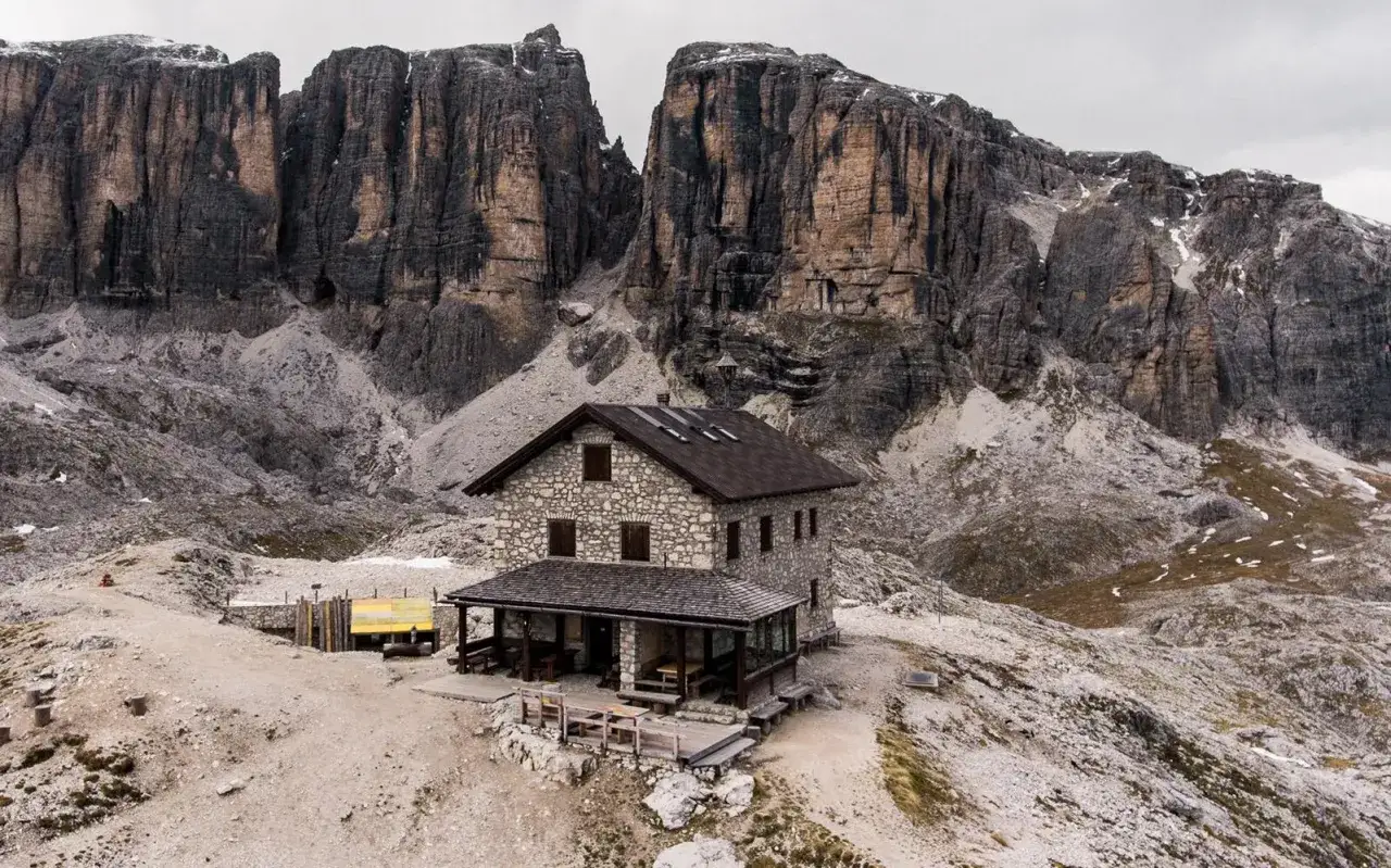 Il rifugio Franz Kostner, un'accogliente costruzione in pietra, si erge maestoso ai piedi di imponenti pareti rocciose dolomitiche.