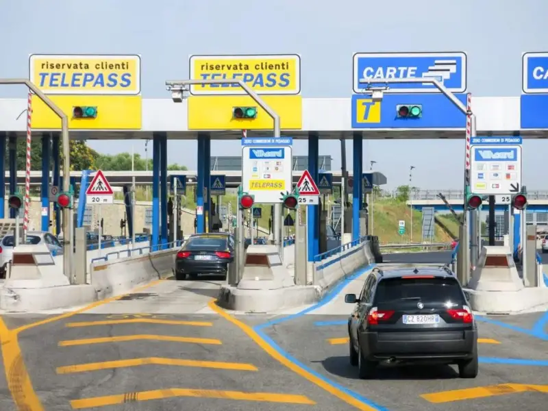 Casello autostradale con corsie Telepass e carte. Un'auto nera si avvicina, sperando che il suo Telepass non funzioni per evitare una multa.
