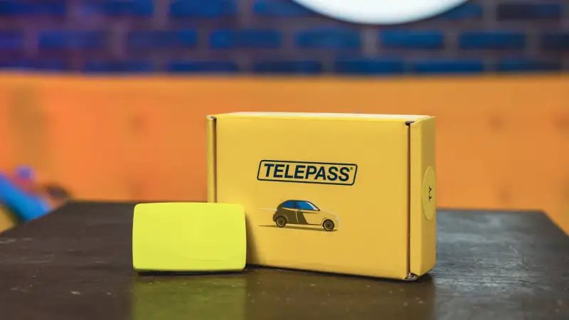 Il dispositivo Telepass e la sua confezione gialla, pronti per il tuo prossimo viaggio. Un comodo recesso telepass per viaggiare senza pensieri.
