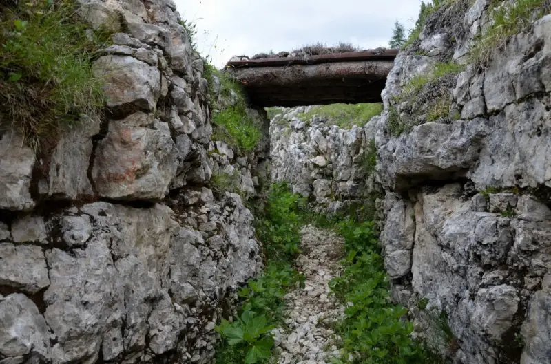Trincea scavata nella roccia sul Monte Ortigara, con un tetto di tronchi. Per sapere come arrivare, cerca sentieri storici.