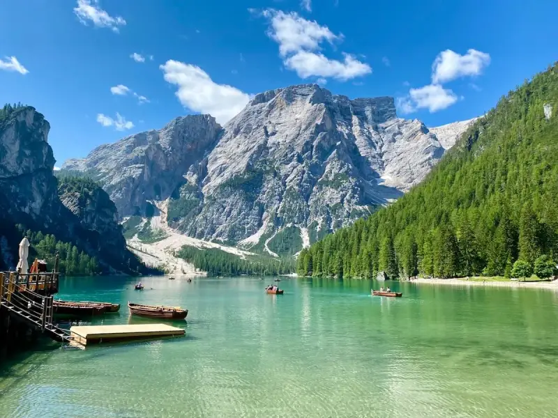 Barche sul **Pragser Wildsee** con montagne imponenti e foreste verdi.